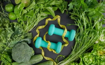 Emagrecimento sustentável: o que realmente funciona? Diversos vegetais verdes, como brócolis e pepino, dispostos ao lado de dois halteres e uma fita métrica, representando os pilares do emagrecimento sustentável e a importância da alimentação saudável.