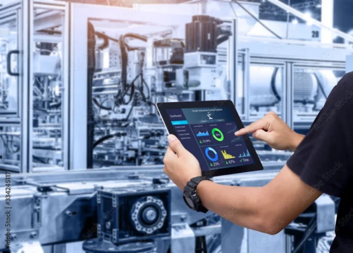 FIESC debate expansão da robótica industrial no Radar Tech Técnico operando um tablet com painel de controle digital em uma fábrica de robótica industrial automatizada. A imagem ilustra o controle e monitoramento para ganho de produtividade e redução de custos, temas centrais do Radar Tech da FIESC.