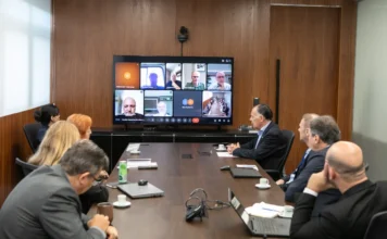 FIESC reformula fóruns e cria novos conselhos industriais Reunião da diretoria da FIESC em Florianópolis para discussão da nova estrutura de conselhos industriais, com executivos ao redor de uma mesa de conferência e participantes via videochamada em uma tela ao fundo.