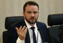 Governo prepara novo Desenrola com uso de FGTS para dívidas O ministro da Fazenda em exercício, Dario Durigan, gesticula com a mão direita enquanto fala em uma mesa de conferência sobre o novo programa Desenrola e o uso do FGTS para renegociação de dívidas.