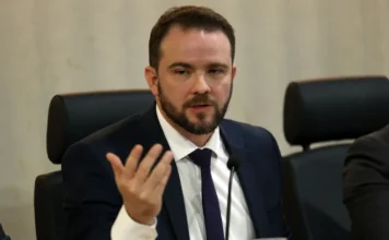 Governo prepara novo Desenrola com uso de FGTS para dívidas O ministro da Fazenda em exercício, Dario Durigan, gesticula com a mão direita enquanto fala em uma mesa de conferência sobre o novo programa Desenrola e o uso do FGTS para renegociação de dívidas.