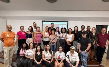 Hemosc realiza encontro sobre desafios da hemofilia em SC Ampla foto de grupo de pacientes com hemofilia, familiares e profissionais de saúde reunidos no auditório do Hemosc em Florianópolis para o IV Encontro da Hemofilia. A cena mostra a comunidade unida na frente de uma tela de projeção, celebrando o Dia Mundial da Hemofilia e a parceria com a Ahesc.