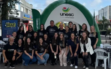 IR na Praça orienta contribuintes e bate recorde de doações Grupo de estudantes e professores de Ciências Contábeis da Unesc e integrantes do NAF reunidos em frente a um portal inflável da universidade durante o evento Imposto de Renda na Praça em Araranguá, vestindo camisetas pretas com a frase Contador com Orgulho.