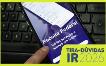 Imposto de Renda 2026: saiba quem é obrigado a declarar Pessoa acessando o aplicativo da Receita Federal no smartphone, exibindo opções como "Meu Imposto de Renda" e "Restituição de Imposto de Renda", sobre um teclado de notebook preto. A imagem tem uma moldura amarela e um bloco de texto no canto inferior direito com o título "TIRA-DÚVIDAS IR 2026" e "Receita Federal", focando na facilidade de acesso a serviços digitais.
