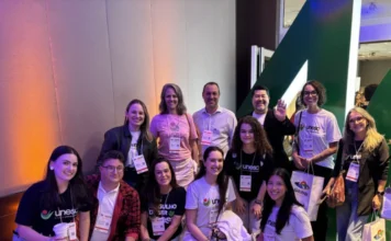 Integratur promove turismo da Amrec na 40ª feira Ugart Equipe do projeto Integratur, parceria entre Unesc e Amrec, reunida durante a 40ª feira Ugart. Profissionais e acadêmicos vestindo camisetas da Unesc posam para foto oficial no evento de turismo em Porto Alegre, focando na promoção do turismo regional do Sul de Santa Catarina.