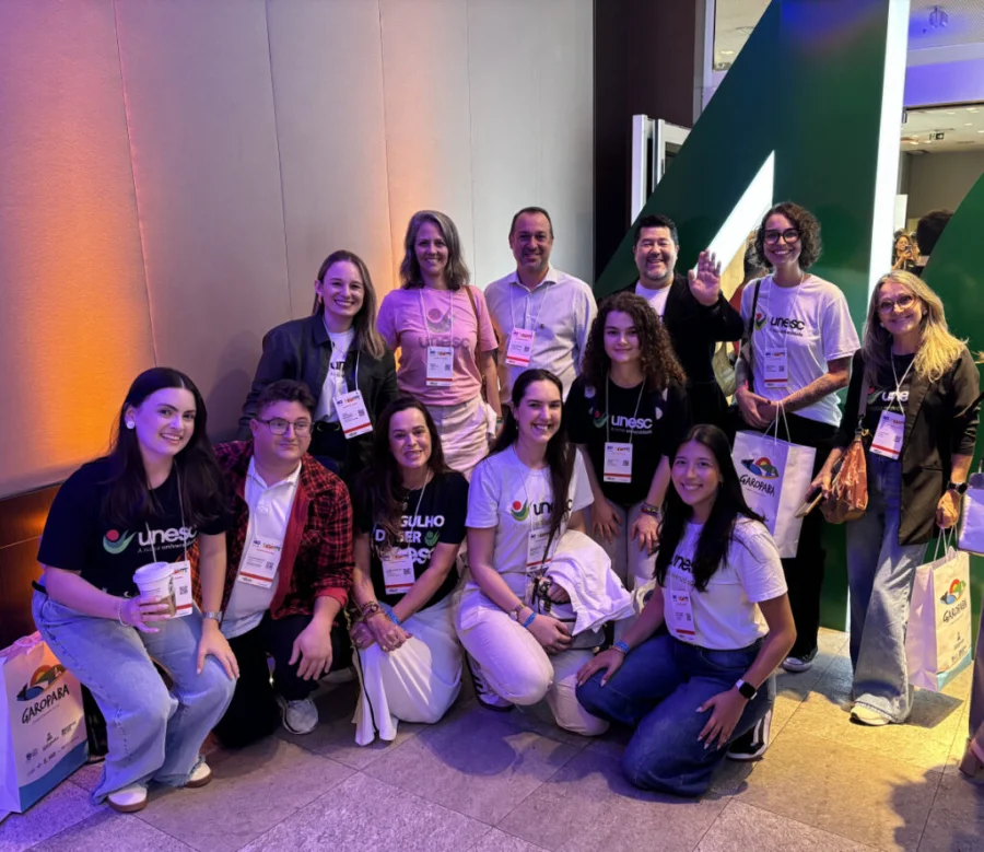 Integratur promove turismo da Amrec na 40ª feira Ugart Equipe do projeto Integratur, parceria entre Unesc e Amrec, reunida durante a 40ª feira Ugart. Profissionais e acadêmicos vestindo camisetas da Unesc posam para foto oficial no evento de turismo em Porto Alegre, focando na promoção do turismo regional do Sul de Santa Catarina.