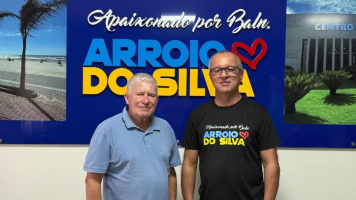 Jairo de Matos assume Secretaria no Arroio do Silva O prefeito Jorge Luiz Freitas e o novo secretário de Administração e Finanças, Amarante Jairo de Matos, posam juntos em frente ao painel institucional da Prefeitura de Balneário Arroio do Silva.