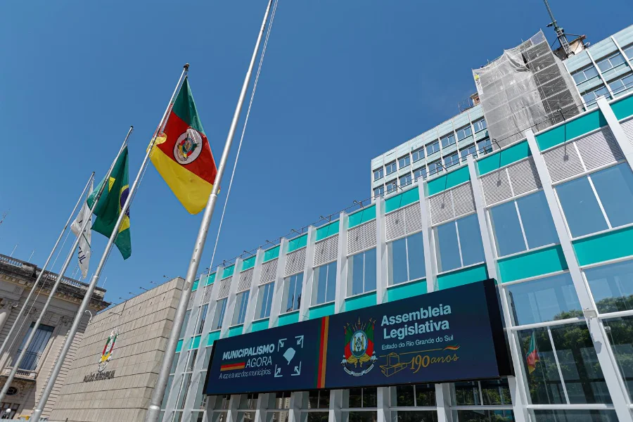 Fachada da Assembleia Legislativa do Rio Grande do Sul (ALRS) em Porto Alegre, com foco nas bandeiras e painel digital dos 190 anos da instituição. Imagem ilustra o cenário político gaúcho durante as trocas de bancadas na janela partidária de 2026.