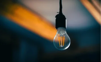 Leilão de energia: Câmara debate risco de alta na conta Lâmpada acesa com filamento em destaque representando o consumo de energia elétrica e o debate sobre o aumento das tarifas e o leilão de reserva de capacidade no setor elétrico.