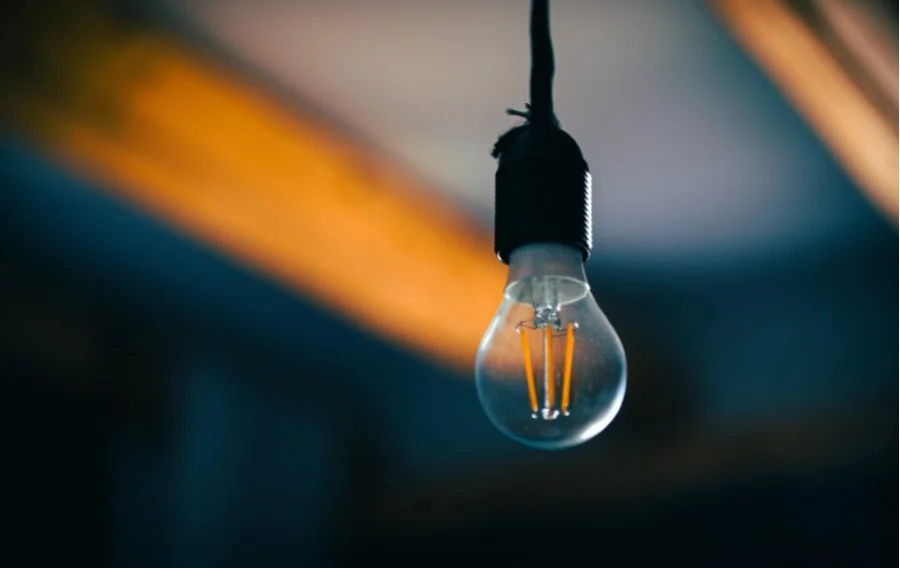 Lâmpada acesa com filamento em destaque representando o consumo de energia elétrica e o debate sobre o aumento das tarifas e o leilão de reserva de capacidade no setor elétrico.