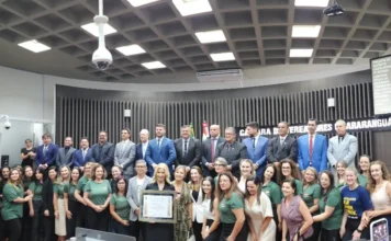 Luciane Ceretta recebe título de cidadã araranguaense Profª. Drª. Luciane Ceretta segura o quadro de Cidadã Honorária cercada por vereadores e equipe técnica na Câmara de Vereadores de Araranguá durante sessão solene.