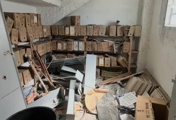 MPSC aponta falhas em escolas municipais de Sombrio Depósito de escola municipal em Sombrio com caixas de documentos, entulhos e materiais de construção descartados de forma irregular, evidenciando a falta de manutenção e riscos estruturais apontados em relatório do MPSC.