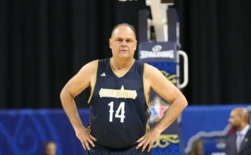 Morre Oscar Schmidt, o maior cestinha do basquete, aos 68 anos Oscar Schmidt, o maior cestinha da história do basquete, posa em quadra vestindo uniforme azul e dourado com o número 14, representando seu legado e trajetória no esporte mundial.