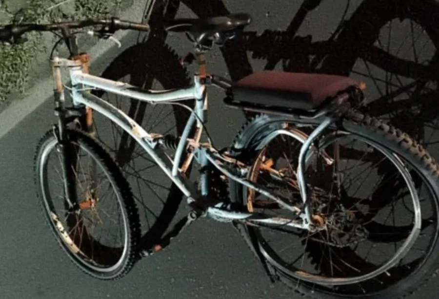 Bicicleta branca com a roda traseira retorcida após colisão causada por motorista embriagado na Avenida Santa Catarina, em Balneário Arroio do Silva. Imagem detalha os danos materiais do acidente de trânsito noturno.