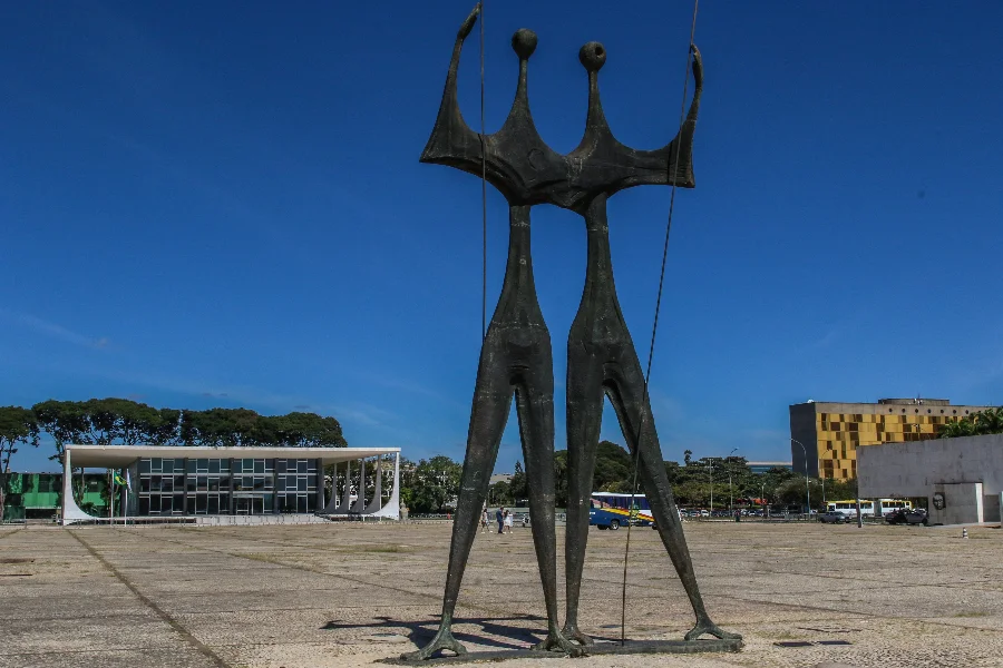 Escultura Os Candangos em destaque na Praça dos Três Poderes, com o edifício do Supremo Tribunal Federal (STF) ao fundo em Brasília. A imagem ilustra a sede da Corte que despende R$ 4,8 milhões anuais em pensões para dependentes de ex-ministros e servidores.