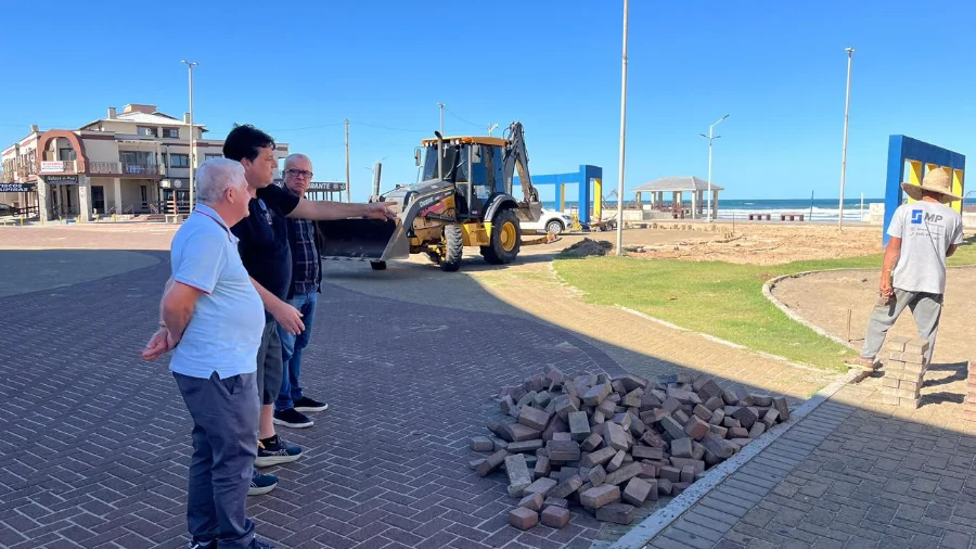 O Prefeito Jorge Luiz Freitas, junto com o Secretário de Administração e Finanças, Amarante Jairo de Matos, e o engenheiro civil, Richard Campos, acompanham o andamento das obras de pavimentação em paver e ampliação do estacionamento na Praça Central de Balneário Arroio do Silva, com trator John Deere ao fundo.