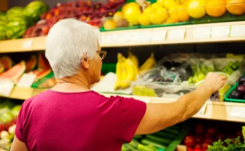 Prévia da inflação sobe 0,89% em abril com alta de alimentos Consumidora escolhendo frutas em prateleira de hortifrúti de um supermercado, ilustrando a alta no preço dos alimentos que impulsionou a prévia da inflação (IPCA-15) em abril de 2026.