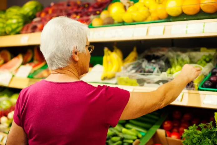 Prévia da inflação sobe 0,89% em abril com alta de alimentos Consumidora escolhendo frutas em prateleira de hortifrúti de um supermercado, ilustrando a alta no preço dos alimentos que impulsionou a prévia da inflação (IPCA-15) em abril de 2026.