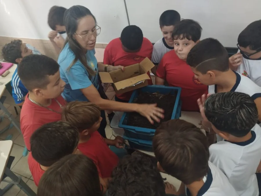 Professora demonstra a atividade de compostagem para alunos em sala de aula da Escola Professor Mota Pires em Araranguá, SC. A atividade integra o projeto de agroecologia da Unesc selecionado pelo edital nacional SBPC vai à Escola. Os estudantes observam a composteira doméstica e o solo orgânico, aprendendo sobre sustentabilidade e educação ambiental do campo.
