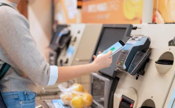 Redução de jornada pode elevar preços em 6,2%, diz CNI Pessoa utiliza smartphone para pagar compras em um caixa de autoatendimento de supermercado. A cena ilustra o impacto no bolso do consumidor e a previsão de alta nos preços de alimentos e serviços devido à redução da jornada de trabalho para 40 horas semanais, segundo a CNI.