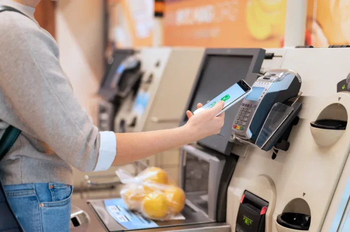 Redução de jornada pode elevar preços em 6,2%, diz CNI Pessoa utiliza smartphone para pagar compras em um caixa de autoatendimento de supermercado. A cena ilustra o impacto no bolso do consumidor e a previsão de alta nos preços de alimentos e serviços devido à redução da jornada de trabalho para 40 horas semanais, segundo a CNI.