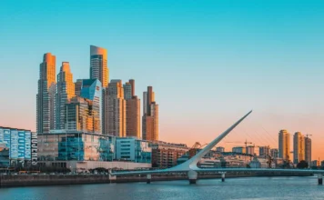 SC bate recorde de exportações para a Argentina em uma década Vista panorâmica de Puerto Madero, Buenos Aires, com a Puente de la Mujer ao pôr do sol. O moderno bairro de negócios da capital argentina brilha com luz dourada, simbolizando o novo clima de negócios e as oportunidades comerciais para exportadores brasileiros, como as indústrias de Santa Catarina, que estão ampliando sua presença no mercado vizinho.