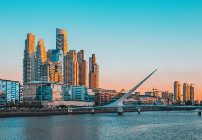 SC bate recorde de exportações para a Argentina em uma década Vista panorâmica de Puerto Madero, Buenos Aires, com a Puente de la Mujer ao pôr do sol. O moderno bairro de negócios da capital argentina brilha com luz dourada, simbolizando o novo clima de negócios e as oportunidades comerciais para exportadores brasileiros, como as indústrias de Santa Catarina, que estão ampliando sua presença no mercado vizinho.