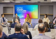 Sefaz-RS encerra Profisco II com avanços tecnológicos Fotografia de oradores em um painel de encerramento do programa de modernização fiscal Profisco II na Sefaz RS. O ecrã de fundo mostra 'Missão Concluída' e os logótipos do BID e do Governo do Rio Grande do Sul. Plateia desfocada em primeiro plano. Foco em gestão tributária e eficiência fiscal.