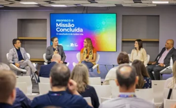 Sefaz-RS encerra Profisco II com avanços tecnológicos Fotografia de oradores em um painel de encerramento do programa de modernização fiscal Profisco II na Sefaz RS. O ecrã de fundo mostra 'Missão Concluída' e os logótipos do BID e do Governo do Rio Grande do Sul. Plateia desfocada em primeiro plano. Foco em gestão tributária e eficiência fiscal.