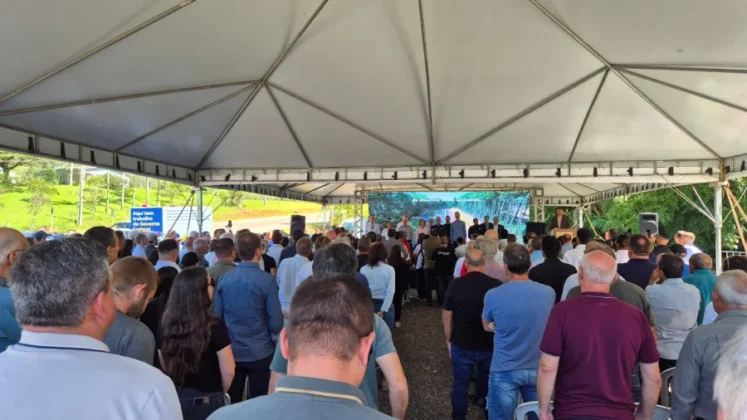 Autoridades e p&uacute;blico reunidos sob tenda oficial durante evento de inaugura&ccedil;&atilde;o da pavimenta&ccedil;&atilde;o da rodovia BR-285 na Serra da Rocinha, em Timb&eacute; do Sul. &Eacute; poss&iacute;vel ver uma placa do Governo Federal ao fundo.