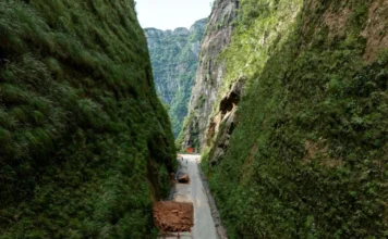Serra do Corvo Branco terá trânsito parcial em 90 dias Vista aérea do trecho sinuoso da rodovia SC-370 na Serra do Corvo Branco, em Santa Catarina, apresentando os paredões de rocha característicos, pista estreita com presença de detritos de terra e sinalização de cones durante as obras de infraestrutura e contenção de encostas.