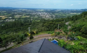 Serra do Faxinal recebe rede trifásica para o turismo Vista aérea panorâmica da Serra do Faxinal em Praia Grande, Santa Catarina, destacando a rodovia SC-290 e a nova infraestrutura de postes da rede trifásica de energia instalada para atender o setor de turismo.