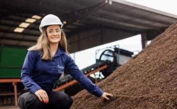 Sombrio transforma lodo de esgoto em adubo e ganha prêmio Profissional da Sombrio Saneamento, Camila Lima, usando EPI e agachada ao lado de uma pilha de fertilizante orgânico produzido a partir de lodo de esgoto tratado na instalação da Composul Compostagem, exemplificando o reaproveitamento sustentável de resíduos.