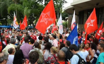 TRE-RJ autoriza PT a parcelar dívida de R$ 570 mil Manifestação política com militantes e apoiadores do PT segurando bandeiras vermelhas da sigla em praça pública, representando a base partidária que aguarda as diretrizes do 8º Congresso.