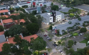 Unesc altera horários devido ao feriado de Tiradentes Vista aérea do campus da Unesc em Criciúma, Santa Catarina, mostrando os blocos universitários, estacionamento com veículos e áreas verdes ao entardecer. A imagem ilustra a unidade que terá horários de funcionamento alterados durante o feriado de Tiradentes.