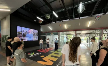 Unesc amplia ações de saúde física para seus funcionários "Grupo de colaboradores da Unesc realiza exercícios de ginástica laboral e alongamento postural no saguão da universidade, focando na saúde e bem-estar do trabalhador. O logo da Unesc está visível no adesivo de chão."