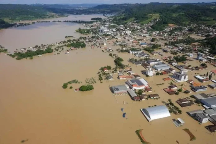 Alesc debate prevenção a chuvas intensas em SC Área urbana alagada em Santa Catarina após chuvas intensas, com ruas, casas e prédios cercados pela água durante enchente