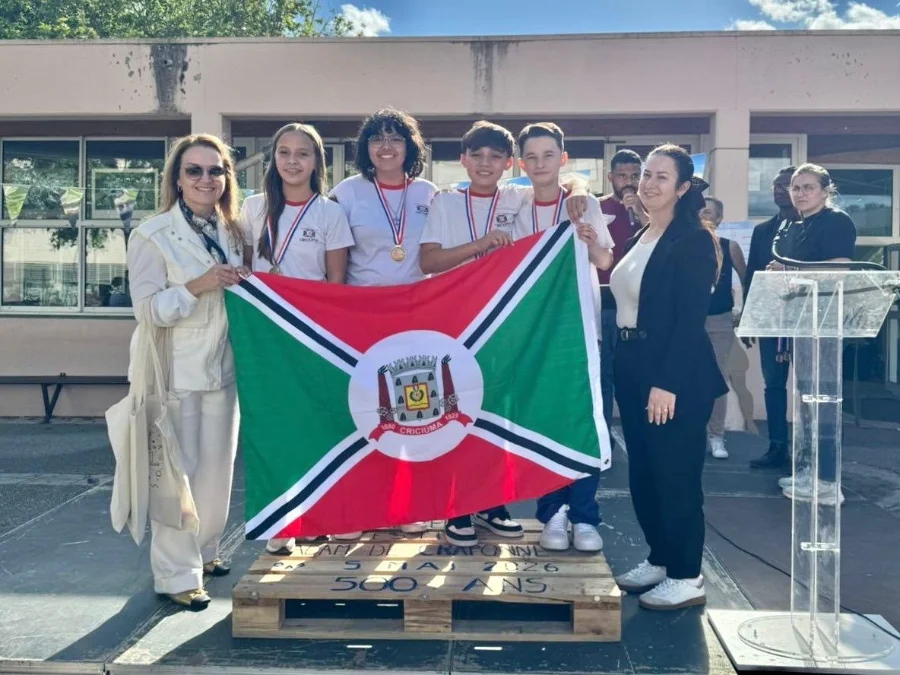 Estudantes de Criciúma medalhistas de ouro na Olimpíada Internacional Matemática Sem Fronteiras, na França, seguram bandeira do município