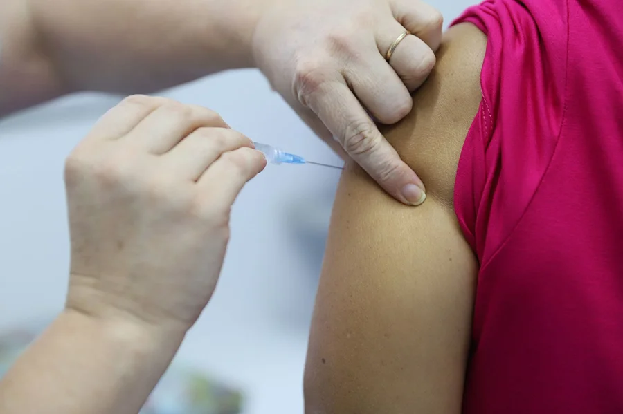Vacinação contra gripe em Criciúma com aplicação de dose contra Influenza no braço de paciente durante campanha de imunização.