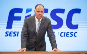FIESC critica fim de imposto para compras de até US$ 50 Presidente da FIESC, Gilberto Seleme, em frente ao painel da entidade, em manifestação sobre imposto de importação para compras internacionais.