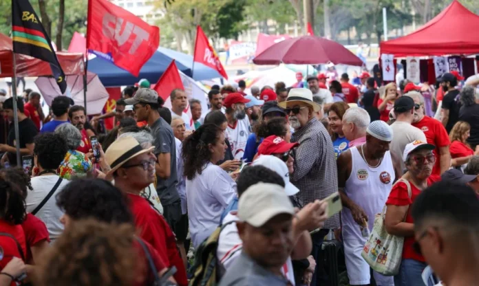 Fim da escala 6x1 marca protestos do 1º de Maio no Brasil Manifestantes reunidos no Eixão do Lazer, em Brasília, durante o ato do Dia do Trabalhador. A imagem mostra uma multidão com bandeiras de centrais sindicais e camisas vermelhas em protesto pelo fim da escala 6x1.