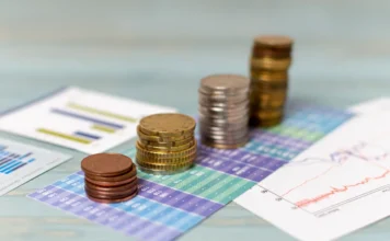 Focus prevê inflação maior e PIB menor Pilhas de moedas sobre gráficos financeiros ilustram projeções do Boletim Focus para inflação, PIB e juros no Brasil.