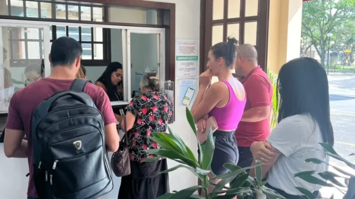 Forquilhinha inicia nova etapa do programa Fila Zero Moradores de Forquilhinha aguardam atendimento em guichê da Secretaria de Saúde para o programa Fila Zero, focado em agilizar consultas e exames especializados. A imagem mostra pessoas em fila na recepção, com cartazes informativos e uma atendente ao fundo, descrevendo o fluxo de serviços públicos para acessibilidade e SEO.