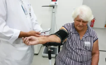 Geração 50+ deve concentrar gastos com saúde em 2044 Idosa passa por atendimento de saúde com aferição de pressão arterial em unidade médica, tema ligado aos gastos da geração 50+ com saúde no Brasil