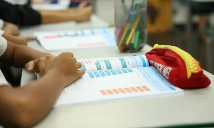 IR dedução para pessoas com deficiência gera dúvida Criança estuda com livro e material escolar em sala de aula; dedução de despesas escolares no Imposto de Renda gera dúvidas para pessoas com deficiência