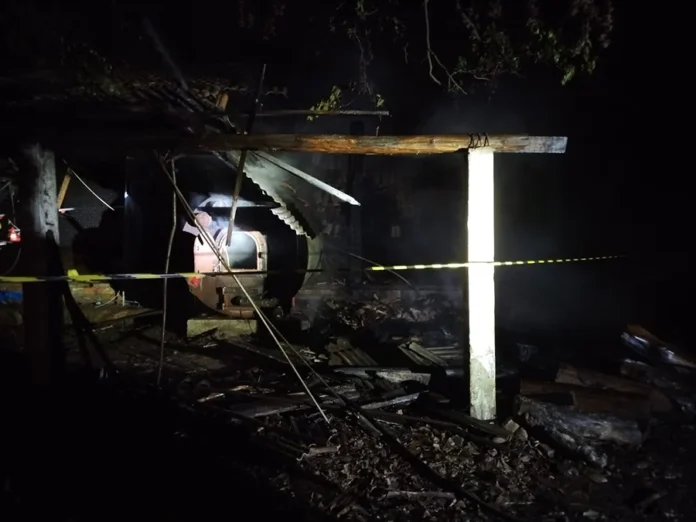Incêndio destrói aviário em Timbé do Sul na madrugada Estrutura destruída de aviário após incêndio em Timbé do Sul com fita de isolamento e fumaça visível ao fundo