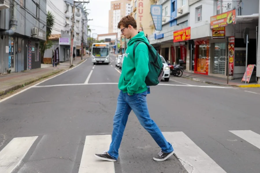 Pedestre atravessa faixa de segurança em rua de Criciúma durante campanha Maio Amarelo de conscientização no trânsito.