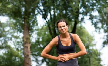 Maio Roxo alerta para doenças intestinais no Brasil Mulher com dor abdominal em área ao ar livre ilustra sintomas de doenças inflamatórias intestinais durante a campanha Maio Roxo.