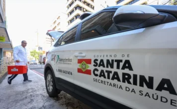Santa Catarina lidera doação de órgãos no Brasil Profissional do SC Transplantes transporta caixa térmica ao lado de veículo da Secretaria de Estado da Saúde de Santa Catarina