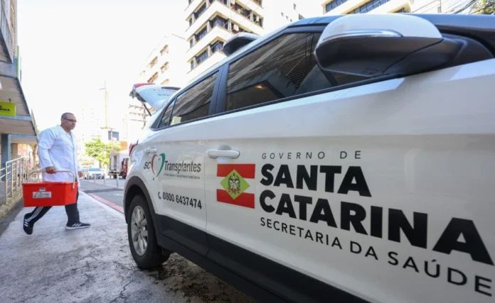 Santa Catarina lidera doação de órgãos no Brasil Profissional do SC Transplantes transporta caixa térmica ao lado de veículo da Secretaria de Estado da Saúde de Santa Catarina